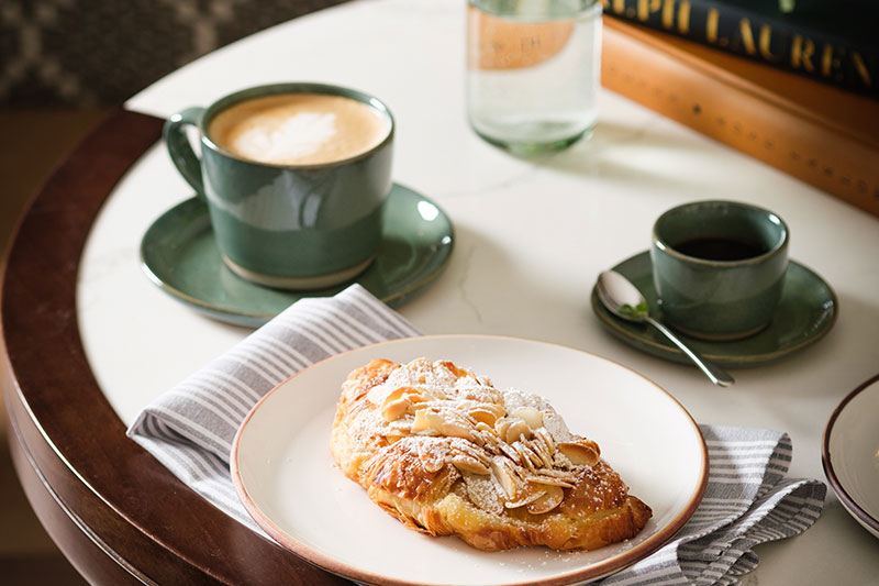 table set for breakfast with greenery, pastry, and coffee
